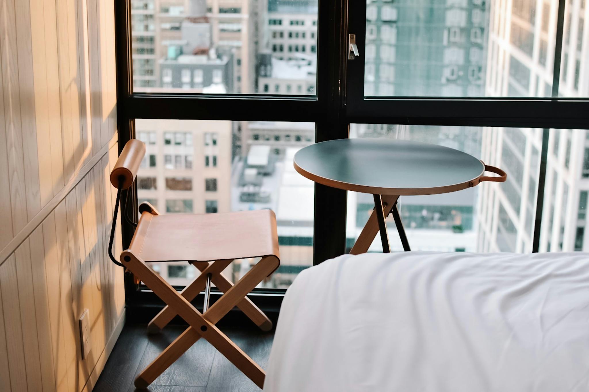 A stylish hotel room in New York City with a cityscape view, blending modern and minimalist design.